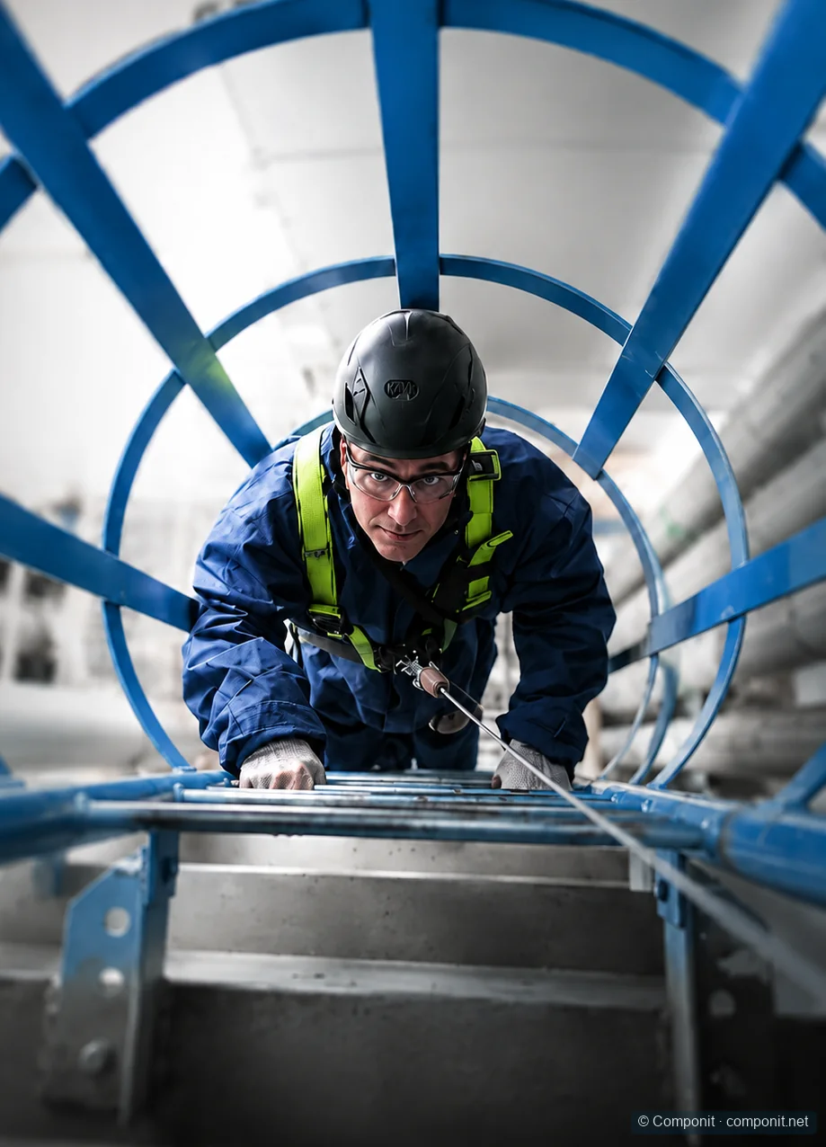 Técnico ascendiendo por una escalera industrial con protección anticaídas